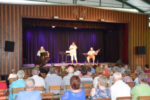 Στη σκηνή διακρίνονται ο μουσικός Patrick Rutka (αρμόνικα), η τραγουδίστρια Charlotte Ludwig και ο μουσικός Klaus Steurer (βιεννέζικη κόντρα κιθάρα).